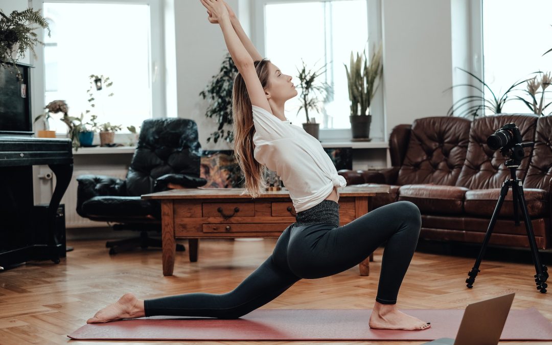 Beautiful sportswoman in yoga posture on floor with laptop and camera