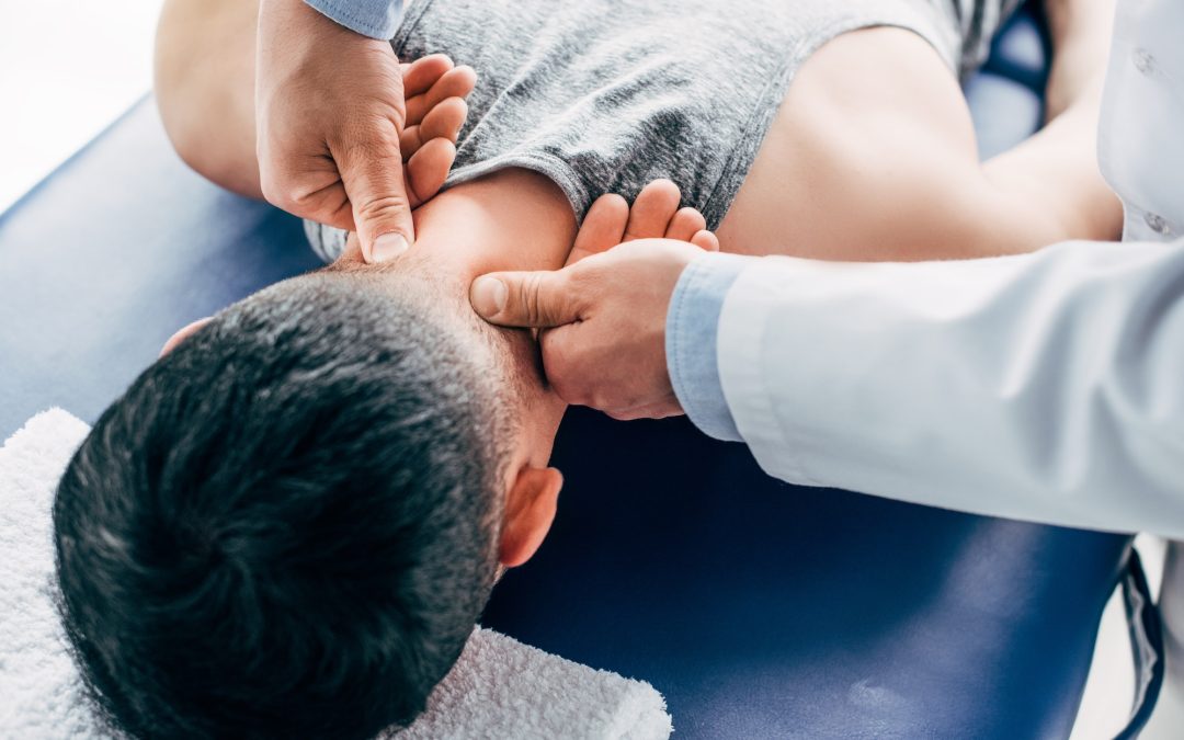 chiropractor massaging neck of man lying on Massage Table with towel