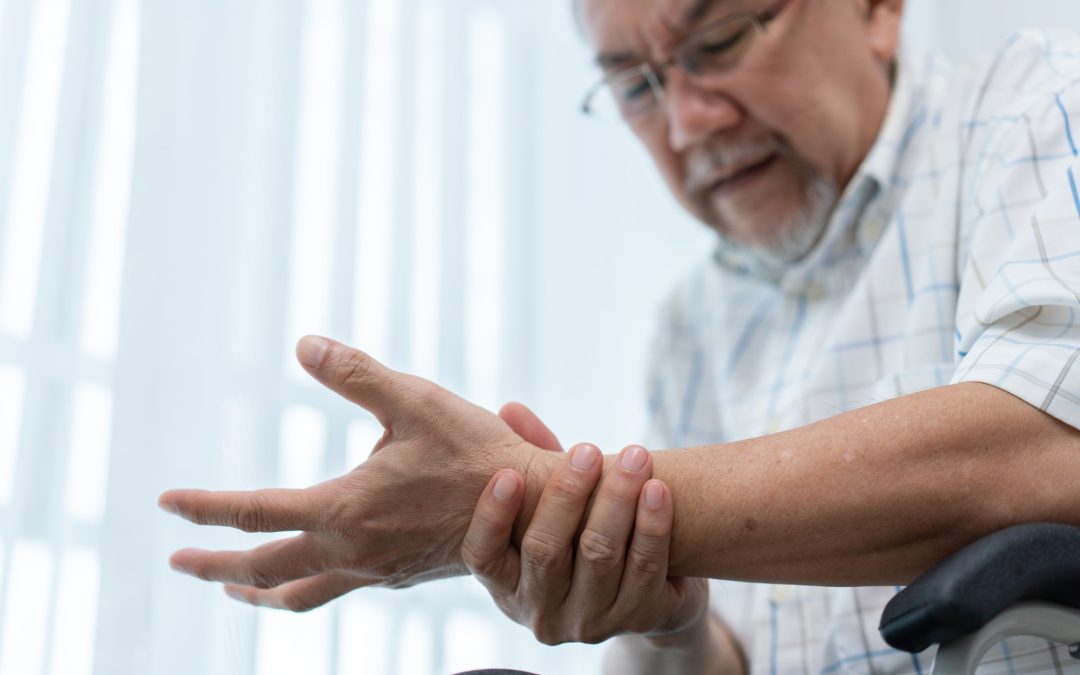 Senior man massaging wrist and arm to relieve suffering from joint pain