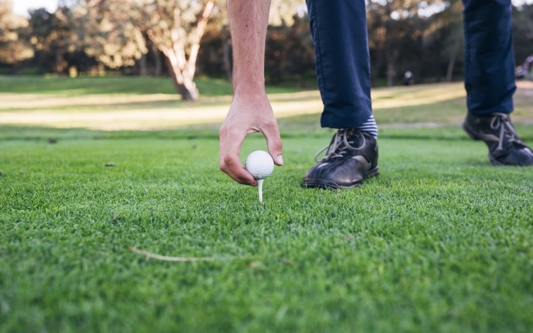 Golfer puts the golf ball on a tee