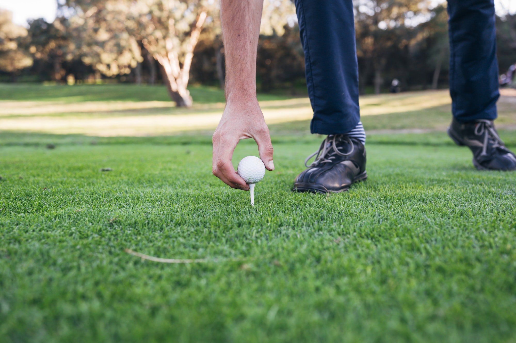 Golfer puts the golf ball on a tee