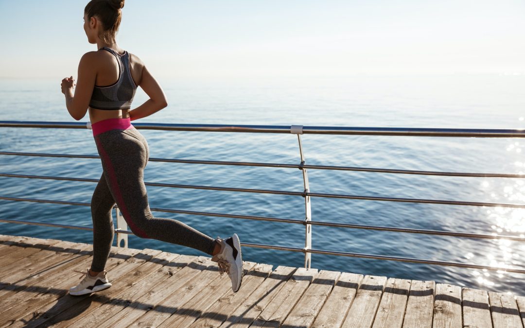Rear view of female athlete workout on the seaside promenade, jogging near sea