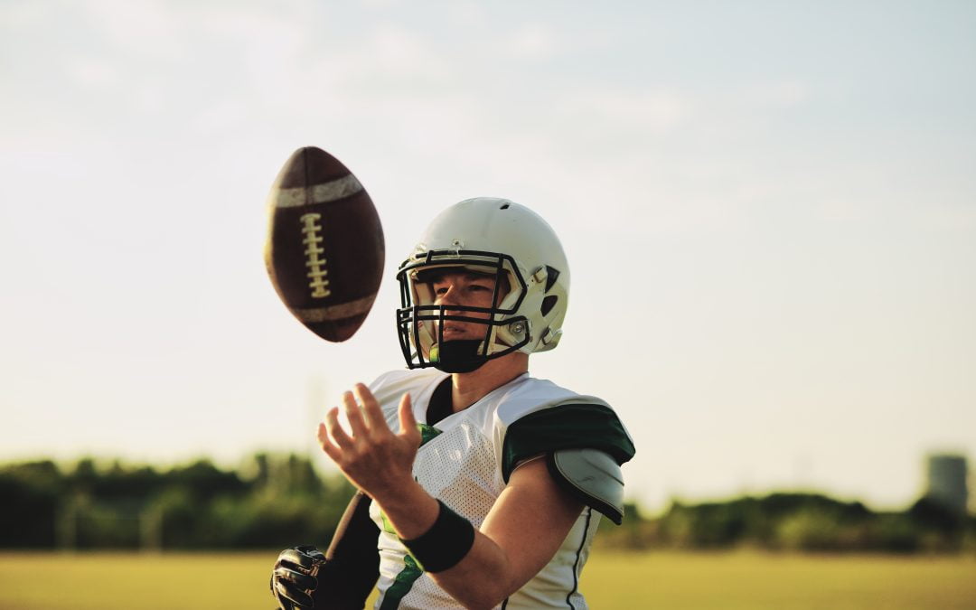 American football quarterback tossing a ball in the air