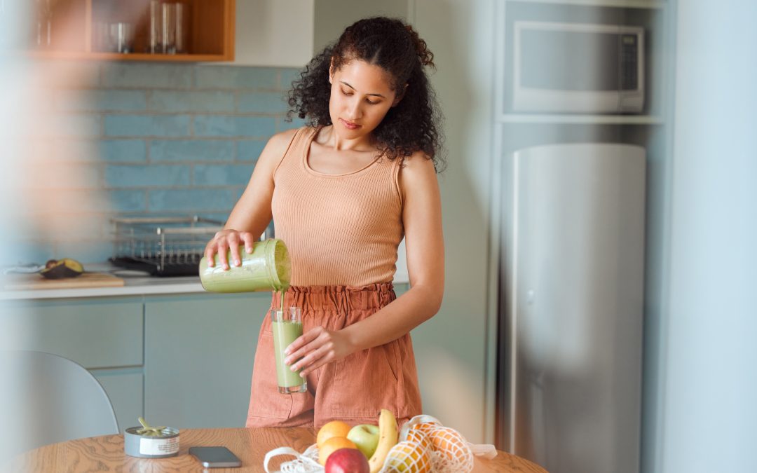 Healthy, nutrition and wellness lifestyle young woman making fresh, green detox fruit smoothie for