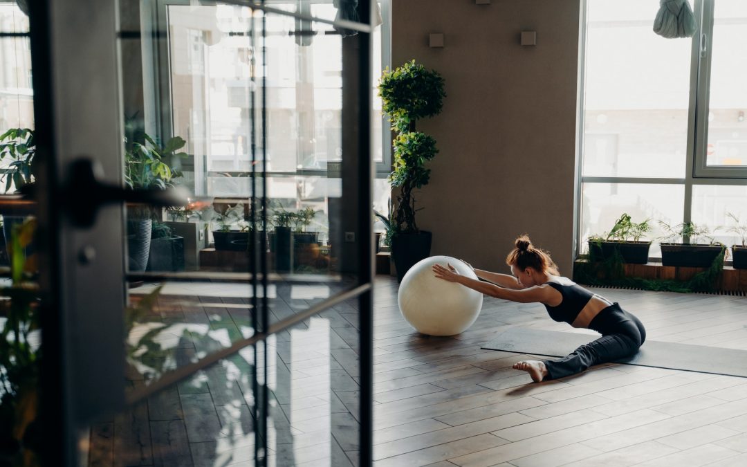 Young woman exercising with fitball, doing stretching exercises in fitness studio